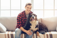 Un homme assis sur un canapé avec son bouvier bernois.